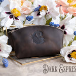 Dark espresso leather makeup bag with an oval crest monogram on a gold tray