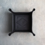 Black leather valet tray with snapped corners and the initials JR pressed into the diamond frame, seen from above