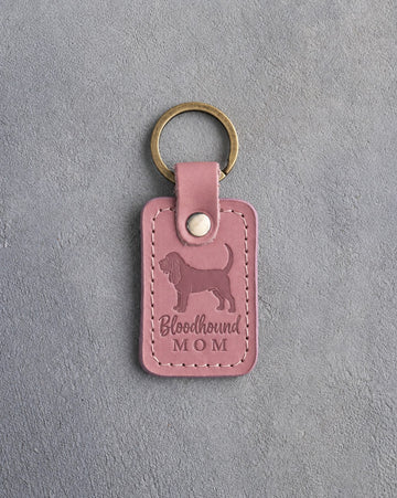 Parisian Blossom pink leather keychain debossed with a Bloodhound silhouette and the words Bloodhound MOM, on gray concrete