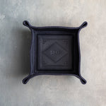 Blueberry leather valet tray with snapped corners and the initials SRG pressed into the diamond frame, seen from above