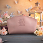 Blush pink leather makeup bag with a floral monogram deboss, roses and a lit lantern in the background