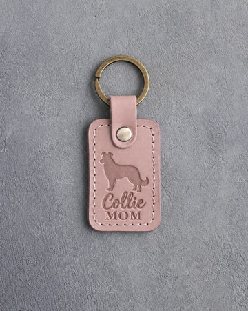 Blush pink leather keychain debossed with a border collie silhouette and Collie MOM lettering, on gray concrete