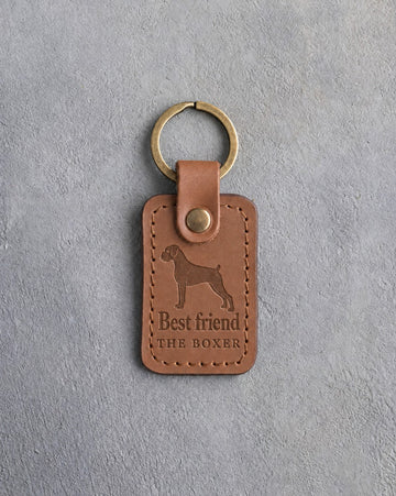 Caramel leather keychain debossed with a Boxer silhouette above Best friend and THE BOXER, on gray concrete