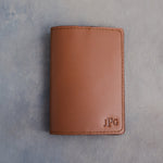Caramel leather passport cover with the monogram JPG with the last initial large pressed into the bottom corner