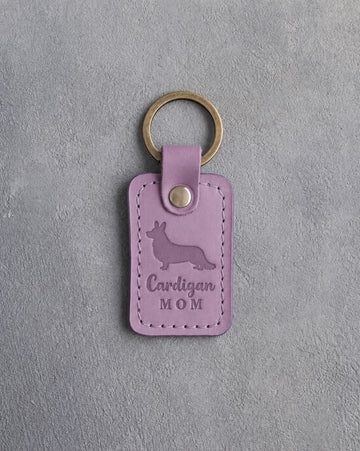 Lilac leather keychain debossed with a Cardigan Welsh Corgi silhouette and the words Cardigan MOM, on gray concrete