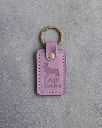 Lilac leather keychain debossed with a Pembroke corgi silhouette and the words Corgi GRANDMA, on gray concrete