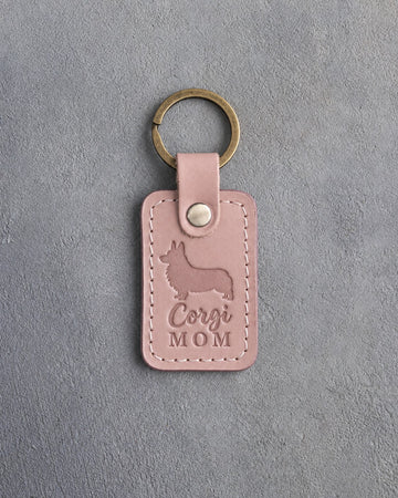 Blush pink leather keychain with a debossed Pembroke corgi silhouette and Corgi MOM lettering on gray concrete