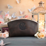Dark espresso leather makeup pouch with an ornate crest-style monogram deboss