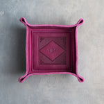 Fuchsia leather valet tray with snapped corners and the initials EJH pressed into the diamond frame, seen from above