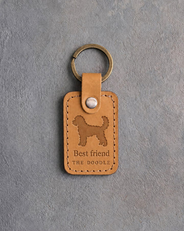 Indian Summer tan leather keychain debossed with a curly goldendoodle above Best friend and THE DOODLE, on gray concrete