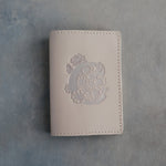 Gray Sand leather passport cover with a large floral initial C pressed into the front