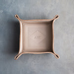 Gray Sand leather valet tray with snapped corners and the initials AHC pressed into the diamond frame, seen from above