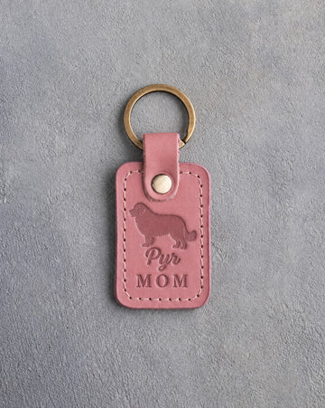 Parisian Blossom pink leather keychain with a debossed Great Pyrenees and the words Pyr MOM, on gray concrete