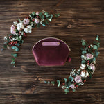 Personalized round leather makeup bag in sangria with a gold nameplate, set in a rose and eucalyptus wreath