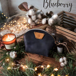 Blueberry navy round leather makeup bag with a leather name patch, cotton stems and a candle nearby
