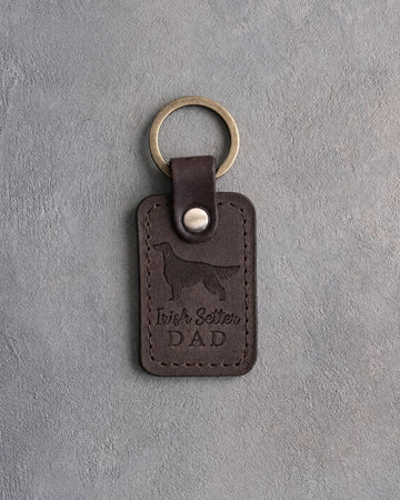 Dark espresso leather keychain debossed with an Irish Setter silhouette and the words Irish Setter DAD, on gray concrete