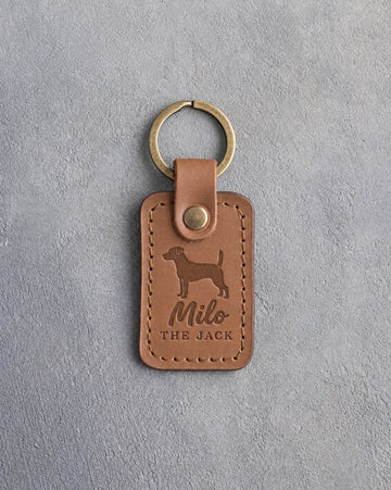 Caramel leather keychain debossed with a Jack Russell terrier above the name Milo and THE JACK, on gray concrete