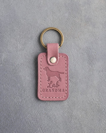 Parisian Blossom pink leather keychain debossed with a Labrador silhouette and the words Lab GRANDMA, on gray concrete