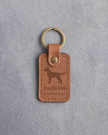 Caramel leather keychain debossed with a Labradoodle silhouette above Doodle love and LABRADOODLE, on gray concrete