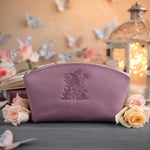 Lilac leather makeup pouch with a floral figure deboss, staged on a slate table