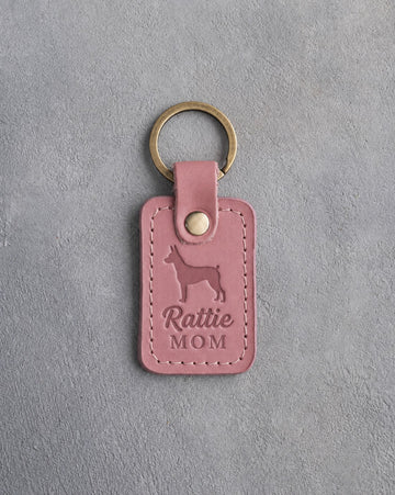 Parisian Blossom pink leather keychain debossed with a Rat Terrier silhouette and the words Rattie MOM, on gray concrete