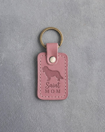 Parisian Blossom pink leather keychain with a debossed Saint Bernard and the words Saint MOM, on gray concrete