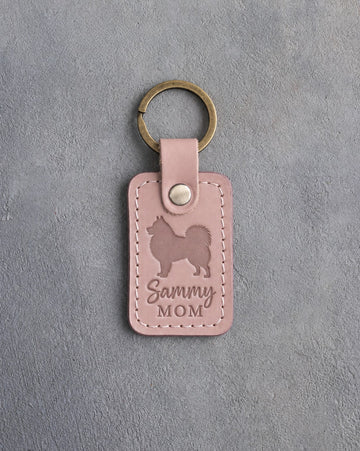 Blush pink leather keychain with a debossed Samoyed and the words Sammy MOM on gray concrete
