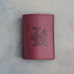 Sangria leather passport cover with a large floral initial L pressed into the front