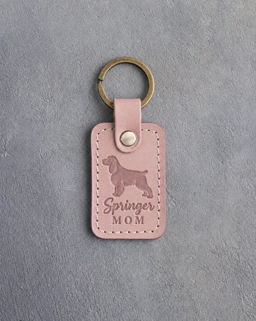 Blush pink leather keychain with a debossed springer spaniel and the words Springer MOM, on gray concrete