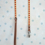 Two thin webbing leashes in cream and red hanging side by side