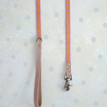 Two thin webbing leashes in pink and marigold hanging side by side