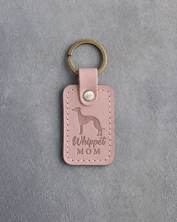 Blush pink leather keychain with a debossed whippet and the words Whippet MOM, on gray concrete