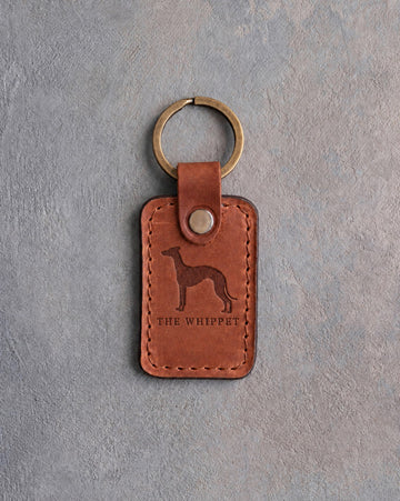 Arizona tan leather keychain debossed with a whippet above THE WHIPPET, on gray concrete
