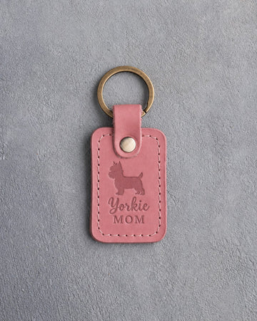 Parisian Blossom pink leather keychain debossed with a Yorkshire Terrier silhouette and the words Yorkie MOM, on gray concrete