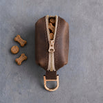 Brown leather zip treat pouch seen from the top, the zipper half open with small dog treats inside