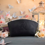 Black leather makeup bag with an ornate floral monogram, framed by roses and paper butterflies