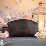 Dark espresso leather makeup pouch with an ornate crest-style monogram deboss