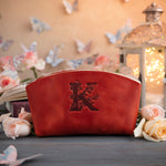 Poppy red leather makeup bag debossed with a floral letter K, roses and butterflies around