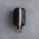 Black leather poop bag holder showing the gold zipper and clip