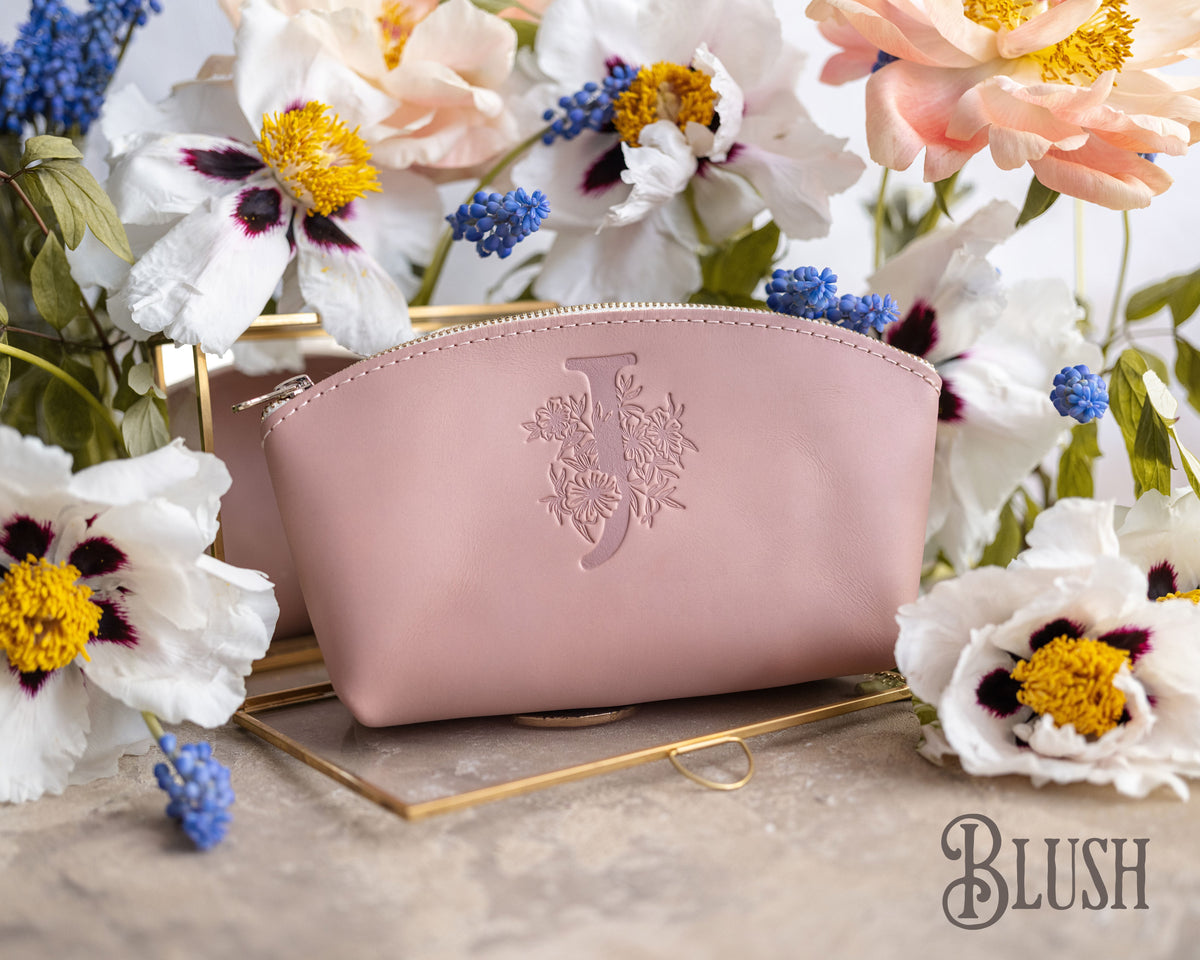 Blush pink leather makeup bag debossed with a floral initial S, white anemones behind