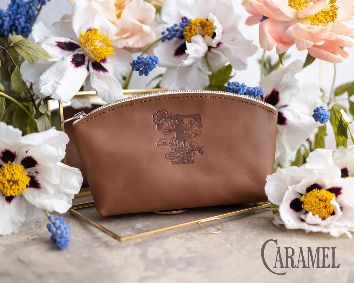 Caramel leather makeup pouch debossed with a floral letter T, white anemones behind