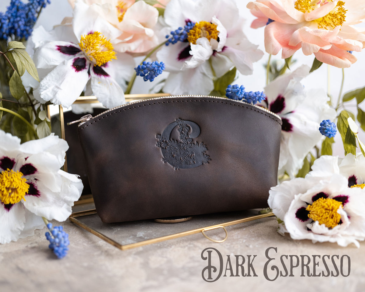 Dark espresso leather makeup bag with an oval crest monogram on a gold tray