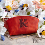 Poppy red leather makeup bag debossed with a floral letter K, white poppies around