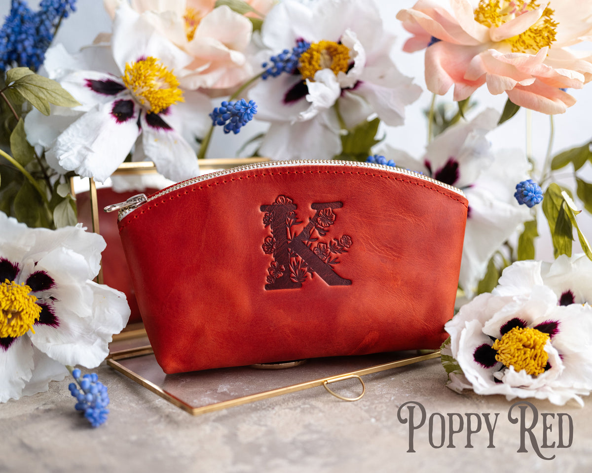 Poppy red leather makeup bag debossed with a floral letter K, white poppies around