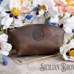Sicilian brown leather makeup bag with an oval crest monogram on a gold tray