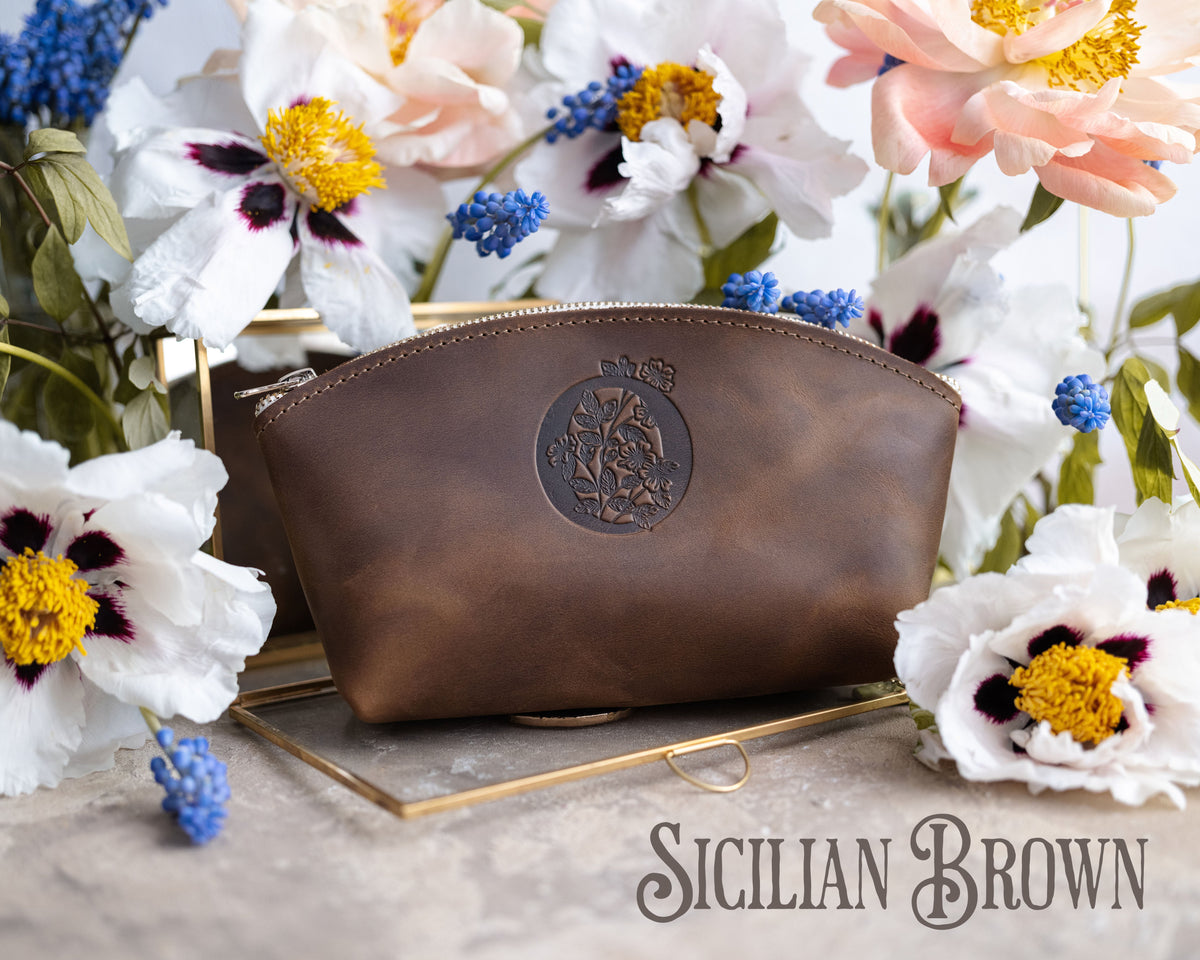 Sicilian brown leather makeup bag with an oval crest monogram on a gold tray