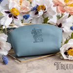 Turquoise pale-blue leather makeup pouch with a floral monogram, white flowers around