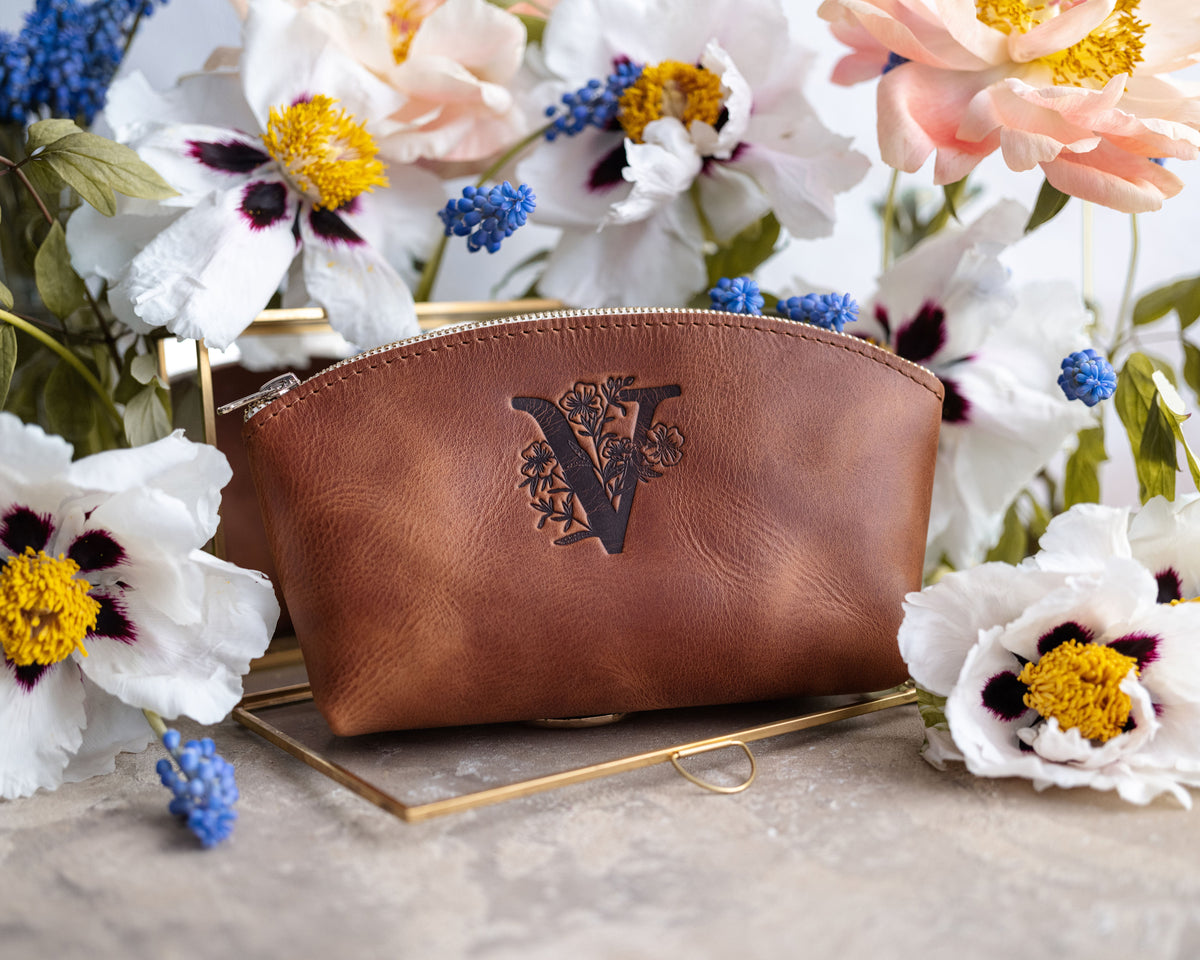 Caramel arizona leather makeup bag debossed with a floral letter V, spring flowers around