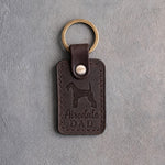 Dark espresso leather keychain debossed with an Airedale terrier and Airedale DAD lettering, on gray concrete