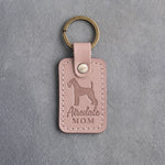 Blush pink leather keychain with a debossed Airedale terrier and the words Airedale MOM, on gray concrete